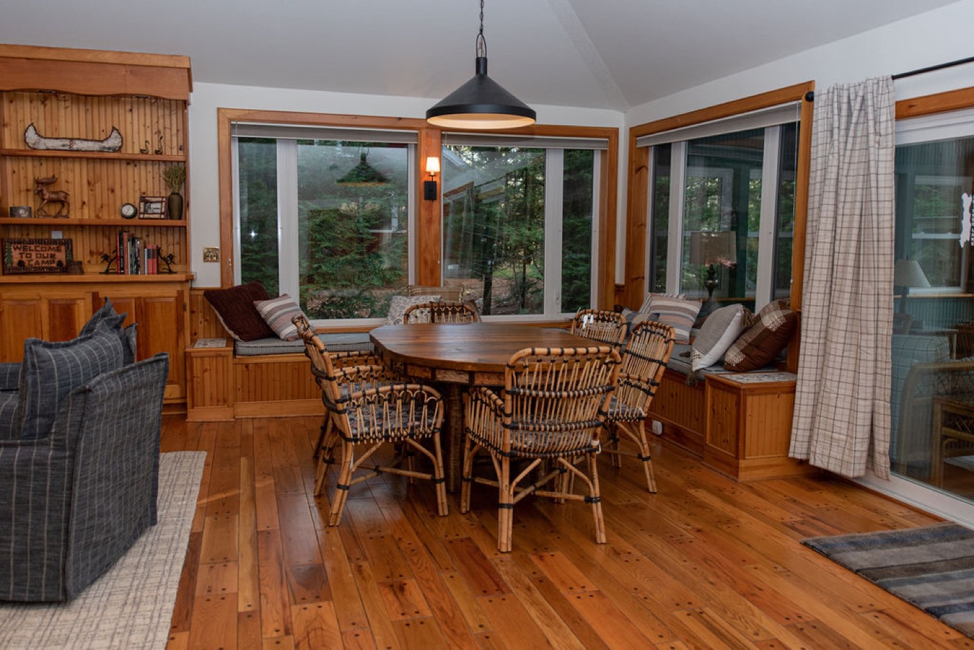 The sunroom dining nook at Camp Sunnyside with rattan chairs and a canoe on the shelf.